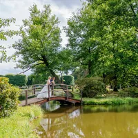 Brautpaar auf einer Holzbrücke im Park am Teich
