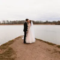 Brautpaar küsst sich auf einer Landzunge am See