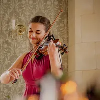 Violinistin im roten Kleid spielt lächelnd Geige