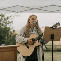 Sängerin mit Gitarre am Mikrofon unter einem Pavillon