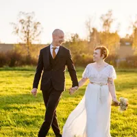 Brautpaar läuft Hand in Hand über eine Wiese