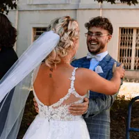 Lachender Gast umarmt die Braut im Freien