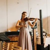 Violinistin im langen Kleid spielt vor Sichtbetonwand