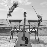 Gitarre vor zwei Traustühlen und Traubogen im Freien