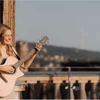 Sängerin spielt lachend Gitarre auf einer Terrasse
