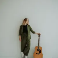 Vanessa steht neben ihrer Gitarre an einer Wand