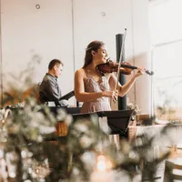 Violinistin spielt, im Hintergrund ein Mann am Klavier