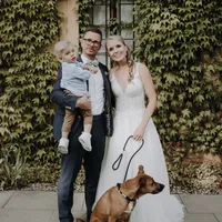 Brautpaar mit Kind und Hund vor Efeuwand