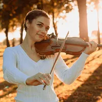 Violinistin spielt Geige im herbstlichen Abendlicht