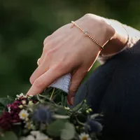 Hand der Braut mit Armband und Brautstrauß auf der Schulter des Bräutigams