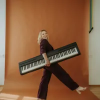 Vanessa trägt lachend ein Keyboard unter dem Arm