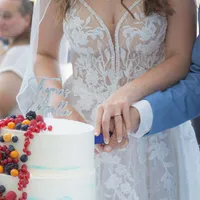 Brautpaar schneidet gemeinsam die Hochzeitstorte mit Beeren an
