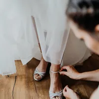 Helferin schließt der Braut die Schuhe