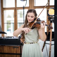 Violinistin spielt vor DJ-Pult und Scheinwerfern