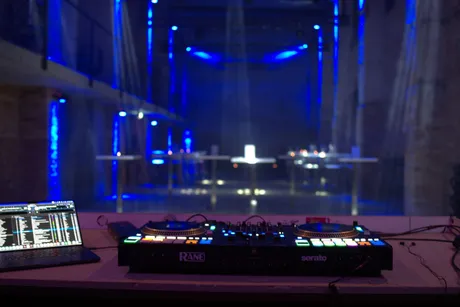 Blick über Mischpult und Laptop von DJ Sascha Juranek in die blau beleuchtete Backsteinhalle des Alten Pumpenhauses