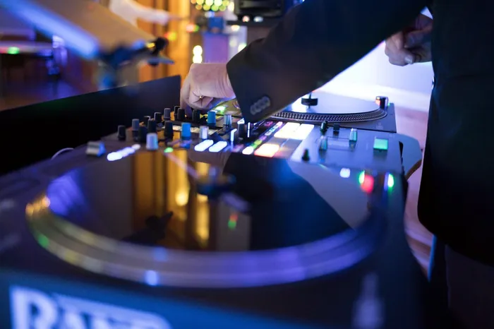 Hände am DJ-Mixer mit Plattenteller und beleuchteten Tasten