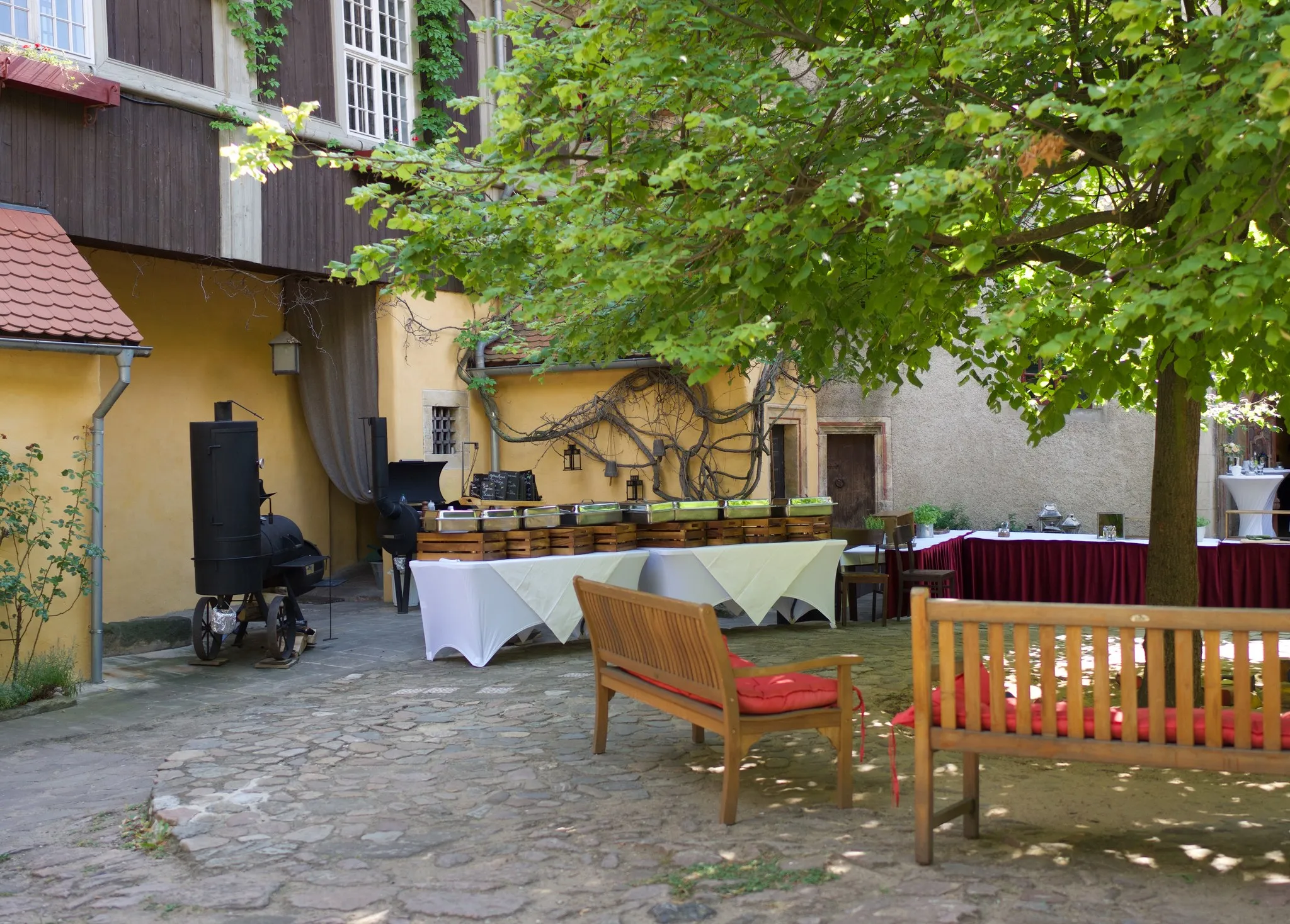 Buffetaufbau im Schlosshof von Schloss Scharfenberg mit Smoker und Holzbänken