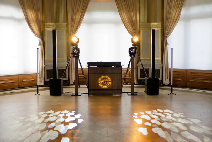 DJ-Pult mit leuchtendem SJ-Logo in einem Festsaal, auf dem Boden Herzen aus Licht