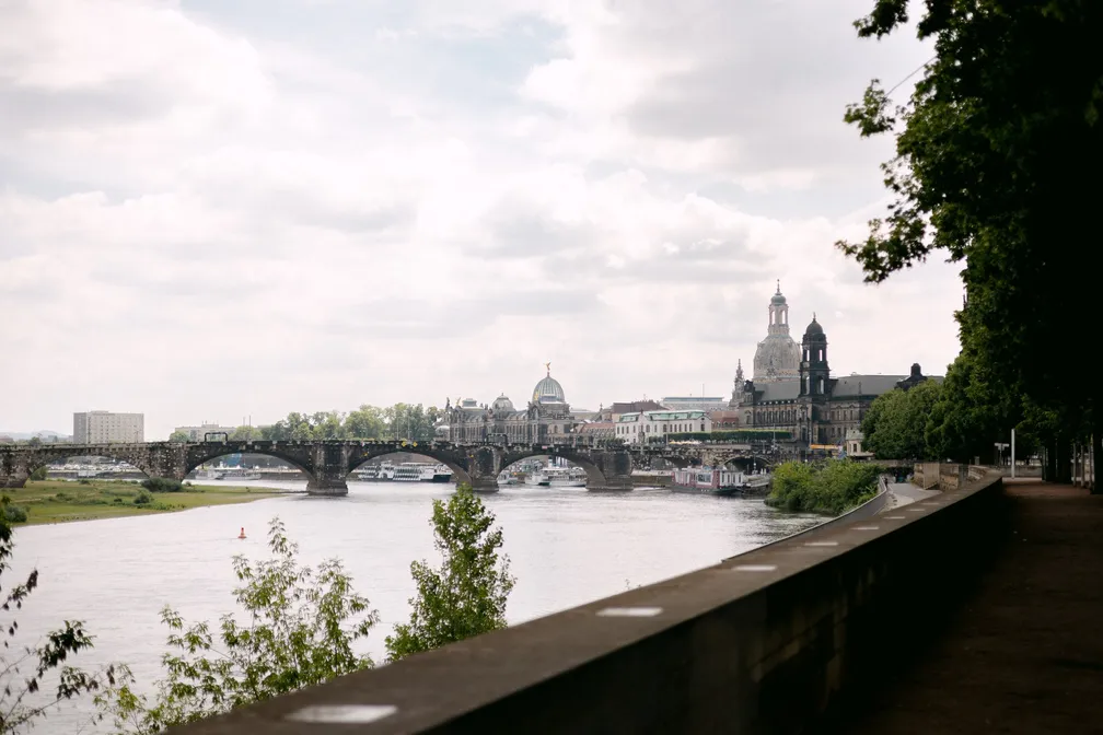 Blick über die Elbe auf die Dresdner Altstadt mit einer Steinbogenbrücke und der Kuppel der Frauenkirche