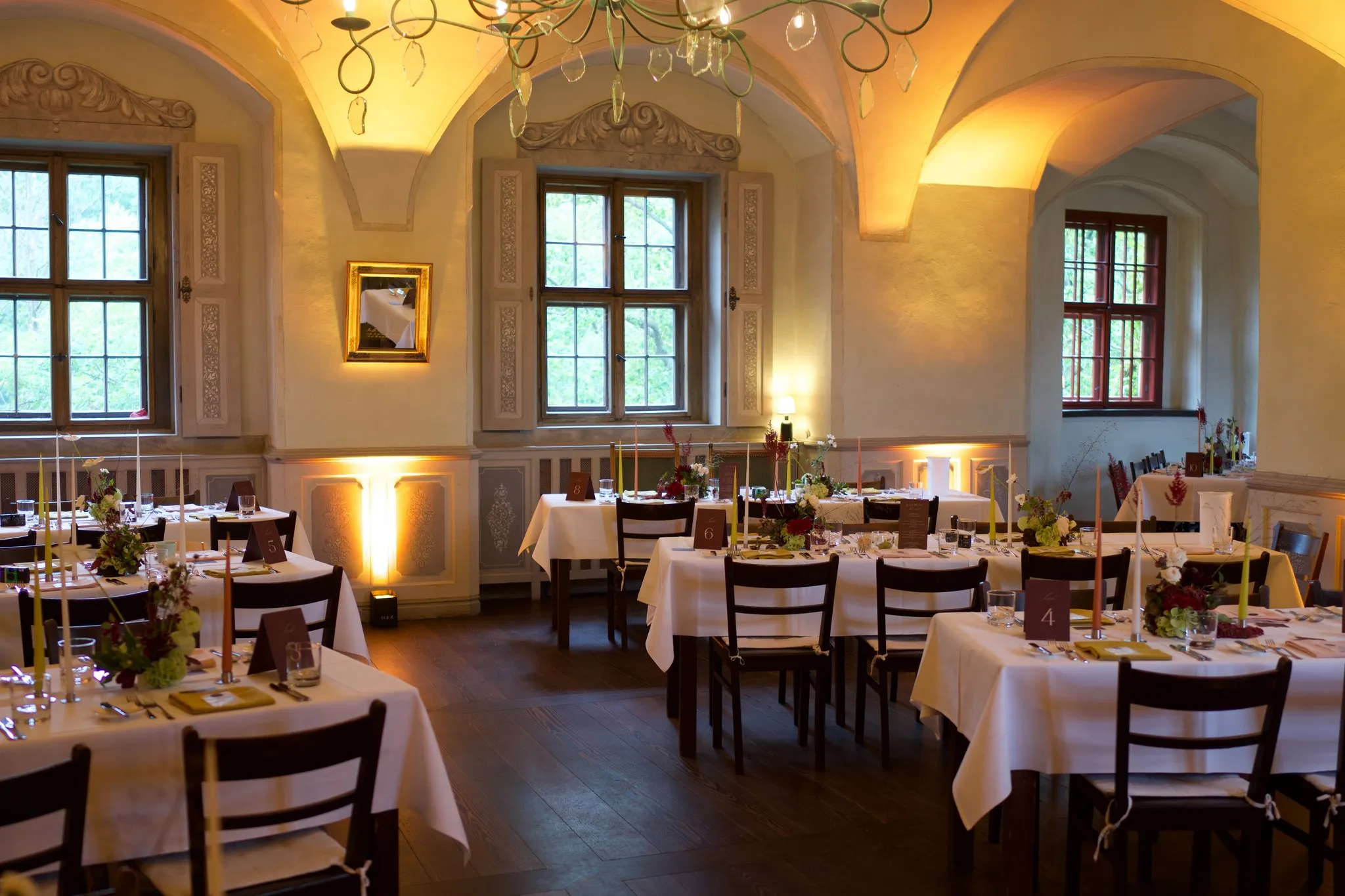 Festsaal von Schloss Scharfenberg mit Kreuzgewölbe, Kronleuchtern und eingedeckten Hochzeitstafeln