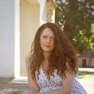 Frau im gemusterten Sommerkleid vor einem historischen Gebäude