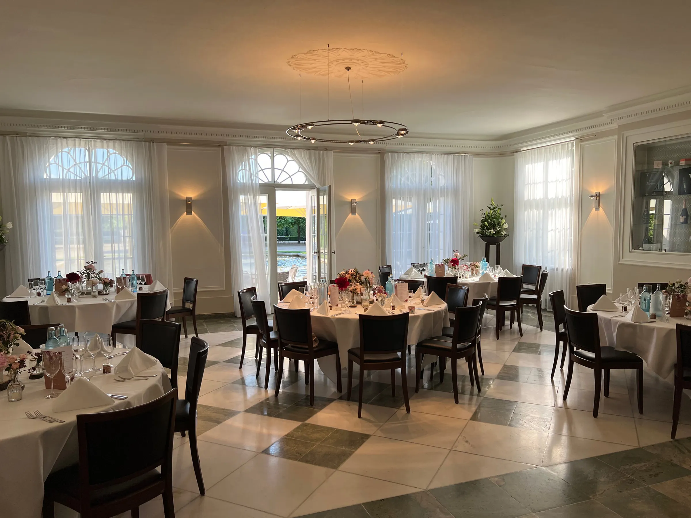 Heller Saal mit runden Tischen und Blumendekoration