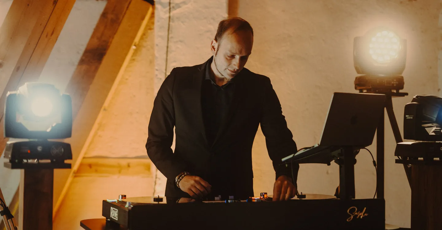 DJ Sascha Juranek am Pult unter einem Dachstuhl