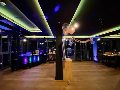 Location mit Happy-Birthday-Girlande und blau-grün beleuchtetem DJ-Pult