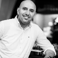 Adel Max Aoun lächelt im weißen Hemd, Schwarz-Weiß-Aufnahme