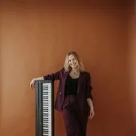 Sängerin Vanessa lehnt lächelnd an einem Keyboard