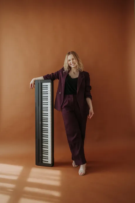 Sängerin Vanessa lehnt lächelnd an einem Keyboard